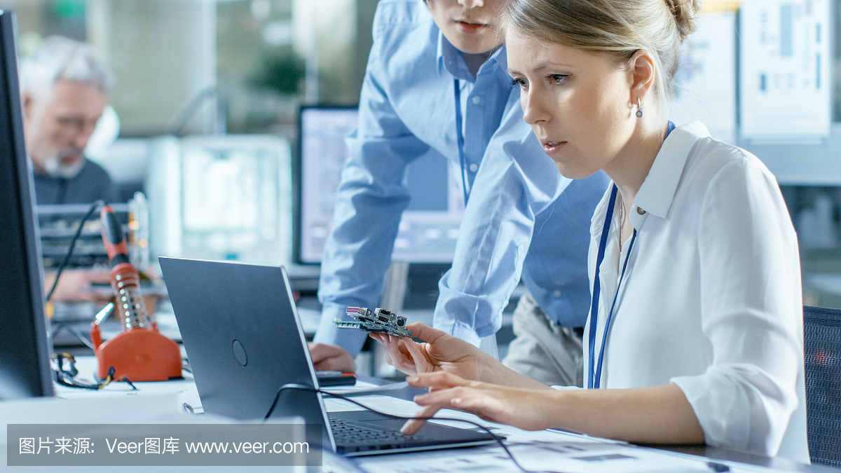 女計(jì)算機(jī)科學(xué)家將電路板連接到她的筆記本電腦并開始編程。她在先進(jìn)技術(shù)實(shí)驗(yàn)室工作。