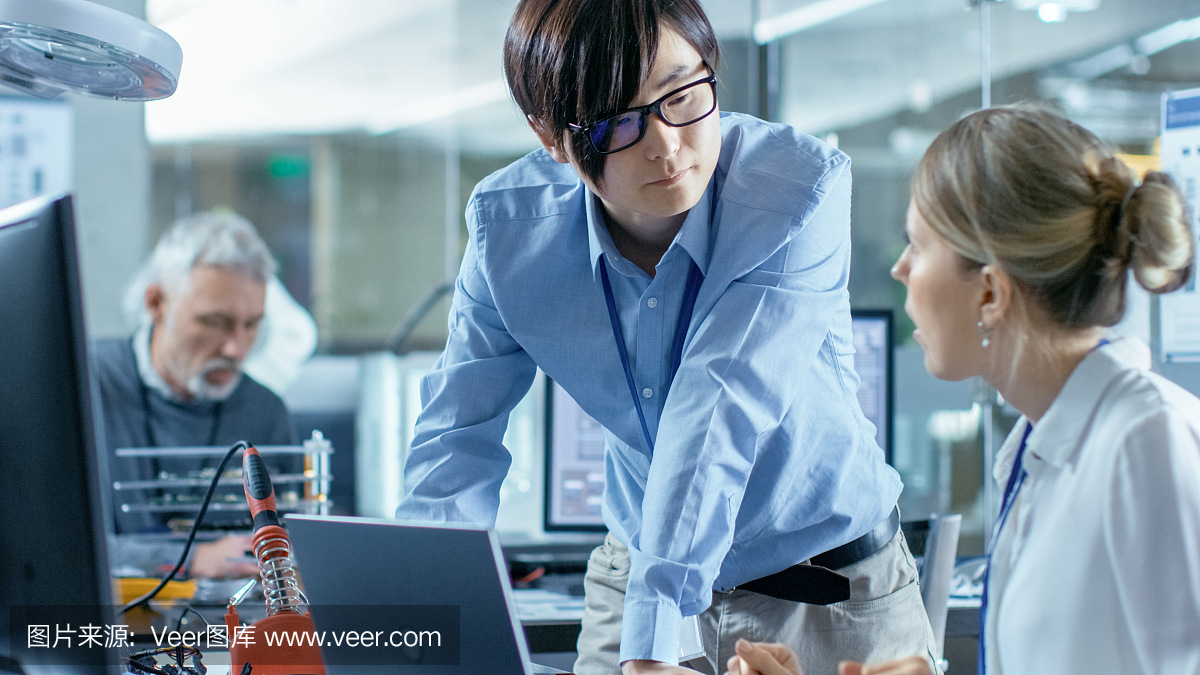 女計算機(jī)科學(xué)家用綠色屏幕模型連接電路板到她的筆記本電腦。她在先進(jìn)技術(shù)實(shí)驗(yàn)室工作。